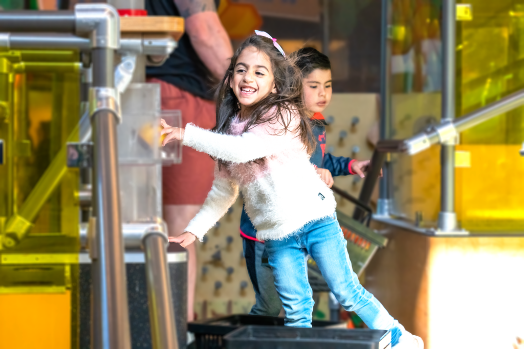 A girl and a boy playing and running at the museum opened space