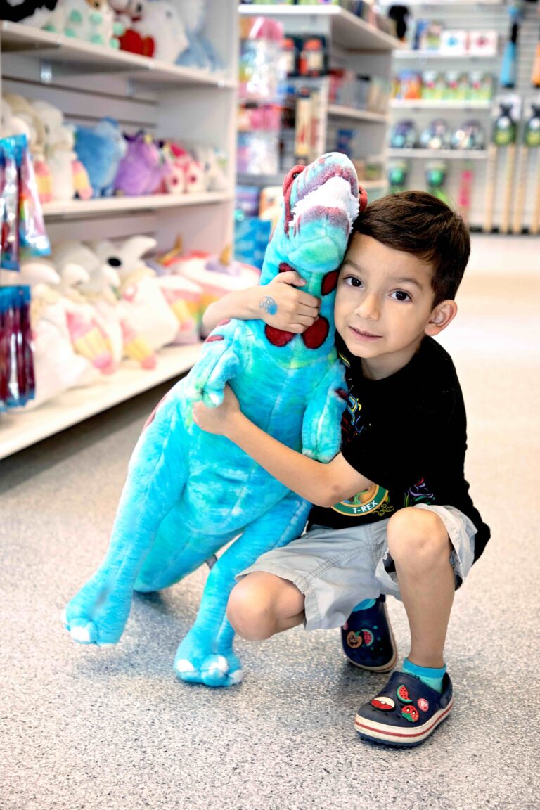 Boy holding plushy dinosaur at the Red Ballon Toy Store