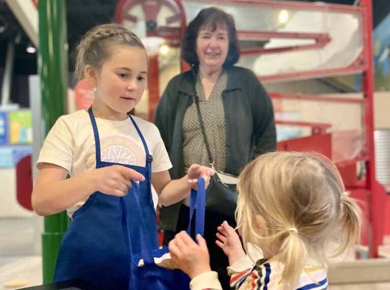 Girl gives baby sister a grocery bag