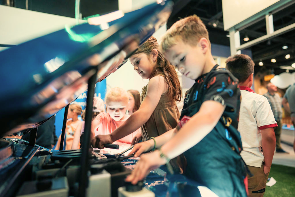 Kids playing at the electric car maintenance station exhibit